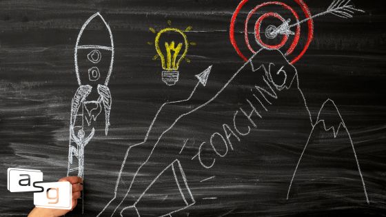 Chalk drawing on a blackboard illustrating the concept of sales coaching. A rocket labeled 'Coaching' is ascending towards a light bulb and a target, symbolizing the launch of ideas and achieving goals in sales coaching.