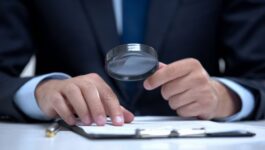 Business professional in a suit examining documents with a magnifying glass, symbolizing the importance of a detailed pipeline review. The image represents deal scrutiny, sales forecasting accuracy, and risk assessment in sales pipeline management.