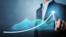 Business professional in a suit pointing at a glowing, upward-trending digital graph, symbolizing successful B2B growth strategies that drive scalable sales, shorten sales cycles, and improve revenue forecasting in 2025.