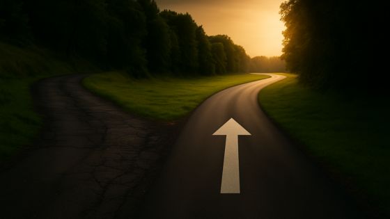 A fork in the road with one illuminated, arrow-marked path representing the choice of an effective sales training program.
